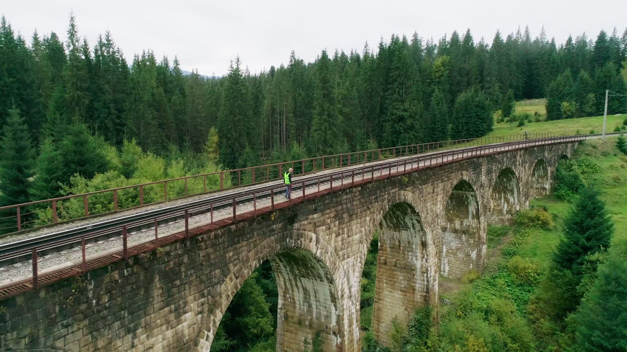 trabajador caminando por el puente ferroviario a través del bosque