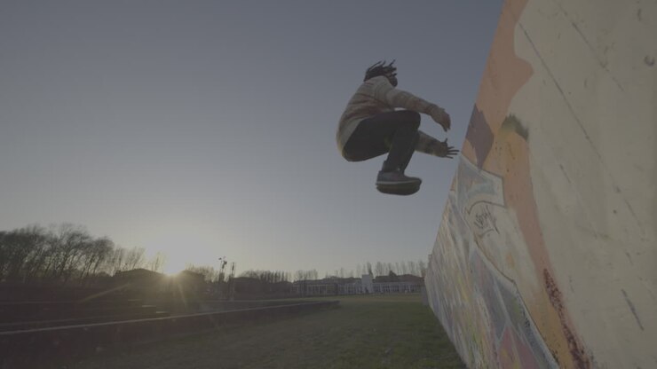 Man jumping over a graffiti wall at sunset