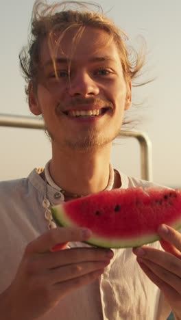 man eating watermelon on a boat
