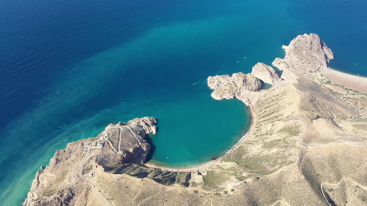 Riprese aeree cinematografiche in 4K di una baia turchese e aspre scogliere desertiche. Mozzafiato paesaggio costiero con acqua cristallina. Ideale per viaggi, vacanze di lusso e documentari sulla natura
