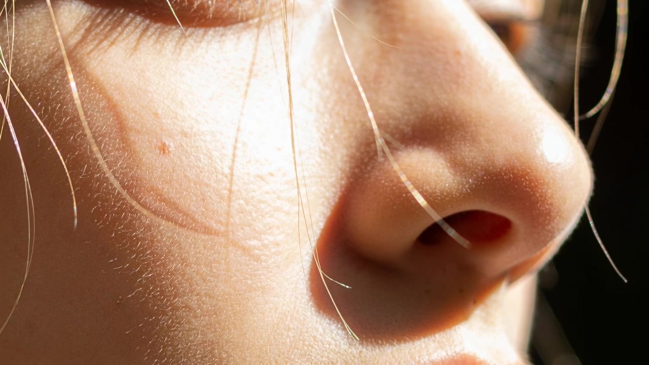 Volto di adolescente che respira, mostrando cambiamenti di luce vicino alla finestra, con una ciocca di capelli che si muove sopra la narice.