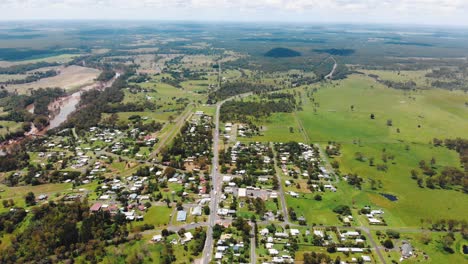 slow flyover of a small town sat in the middle of a vast, flat stretch of green, grassy land under hundreds of soft, white clouds looming overhead