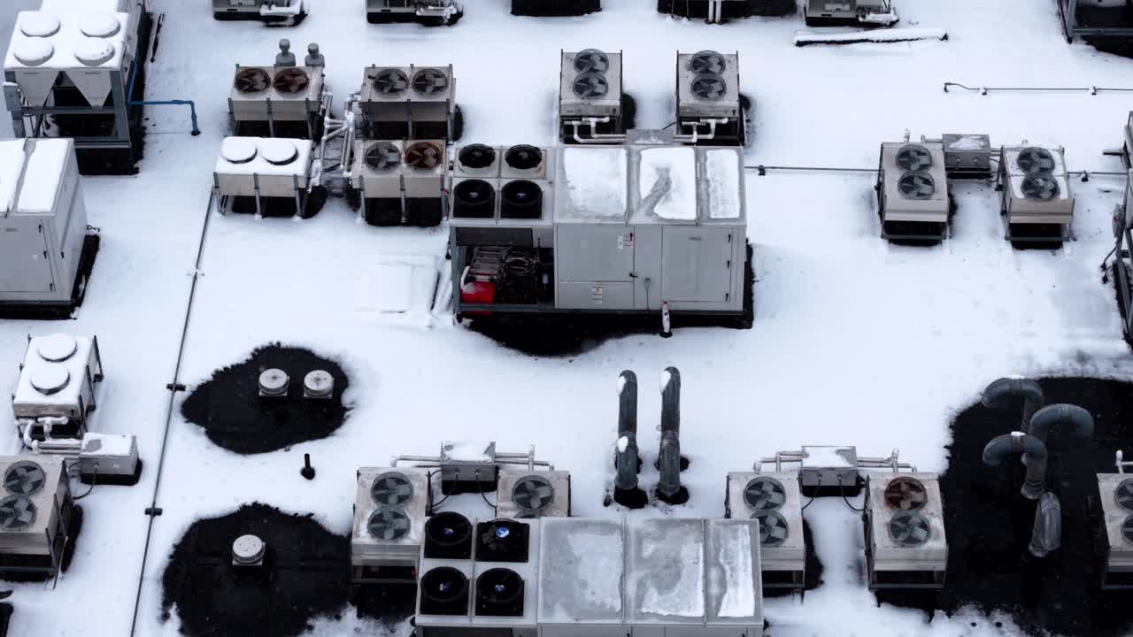 Snow-covered HVAC units seen from above on a cold winter day