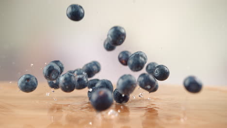 blueberries falling onto the wooden table, bouncing and splashing water droplets around the kitchen in macro and slow motion