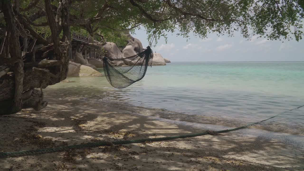 Cena de praia relaxante com rede e barcos ao longe