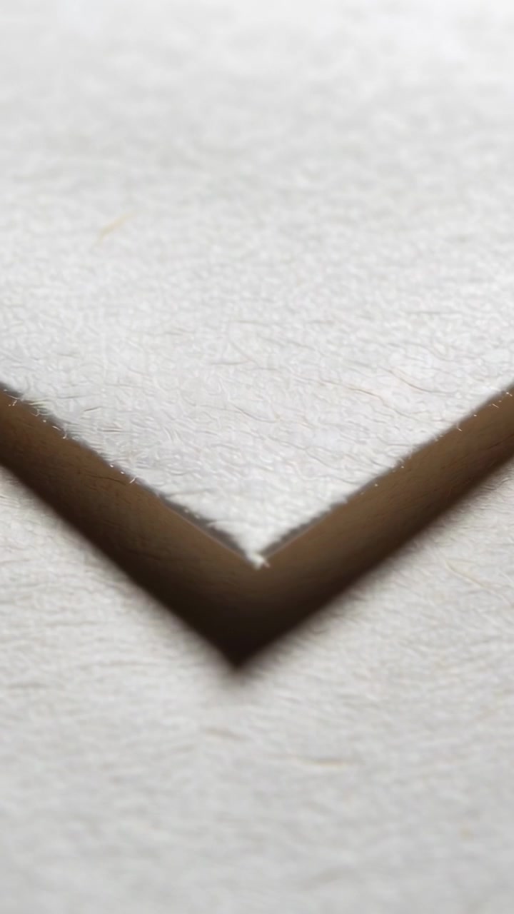Vídeo vertical: Ajustando o foco, movendo o canto em V de um papel para o centro da superfície, mostrando uma fenda sombria.