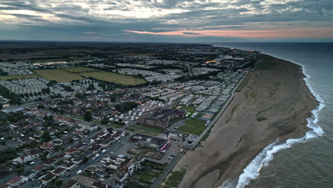 Aerial-drone-video-captures-summer-sunset-over-Skegness,-featuring-holiday-park,-beach,-sea,-and-caravans-on-sweeping-landscapes