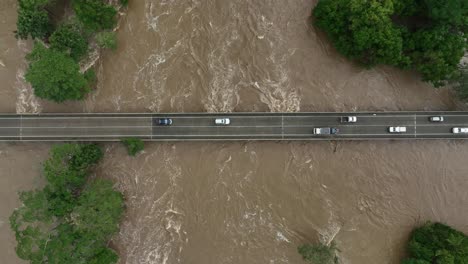 aerial views above cars driving over the barron river bridge at caravonica after the extreme flooding caused by cyclone jasper, cairns