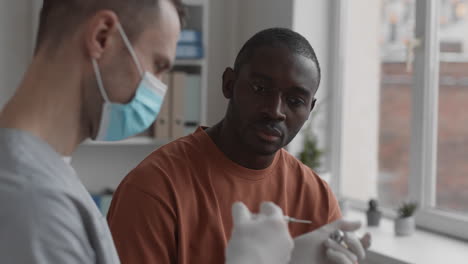 man watching doctor preparing for injection