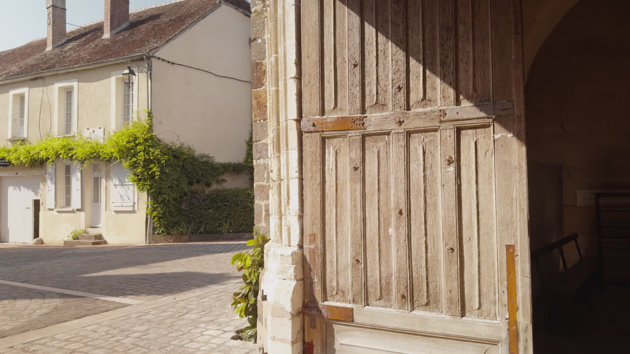 Profile view of old weathered, wooden door with vertical panels at Church of Saint-Fargeau in France during daytime