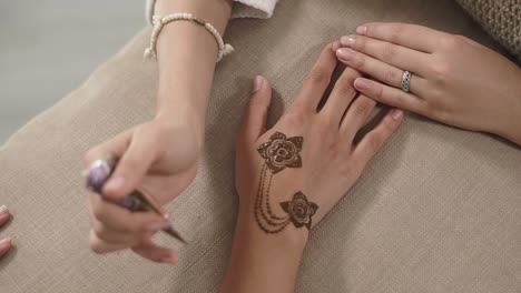aplicación de tatuaje de henna en las manos