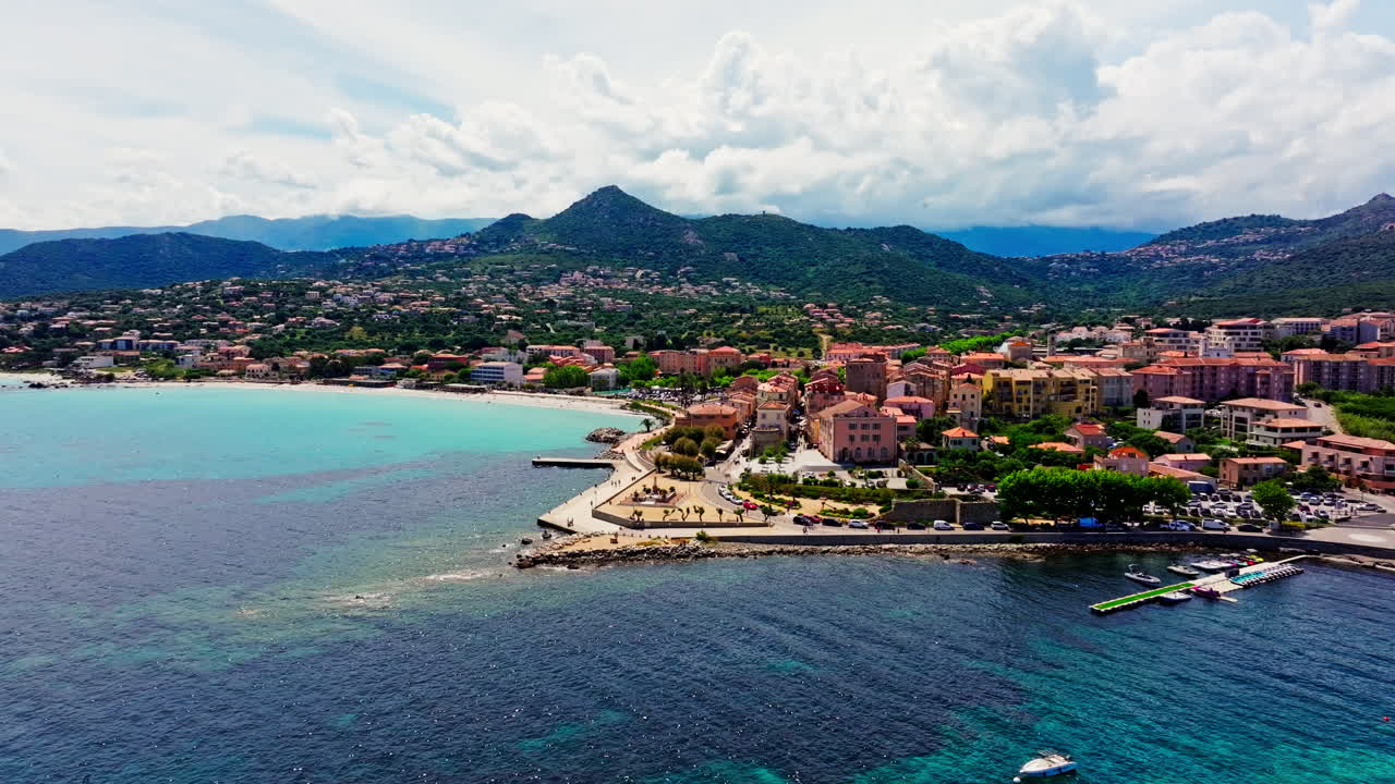 Aerial drone shot over the coastal town Île-Rousse in the Balagne region in Corsica, France. View of the beach and turquoise. Ile de la La Pietra in the