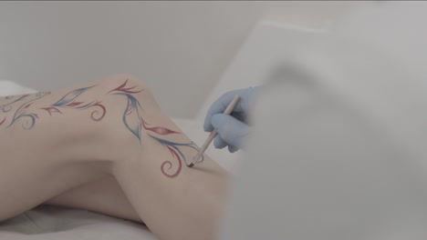 applying temporary floral tattoo design on a leg