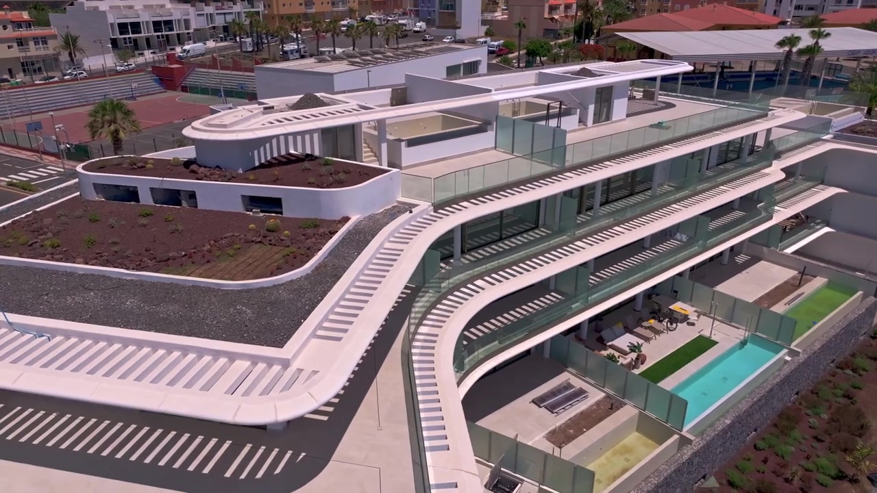 Moderno edificio a più livelli con terrazze panoramiche e piscine in una soleggiata area urbana
