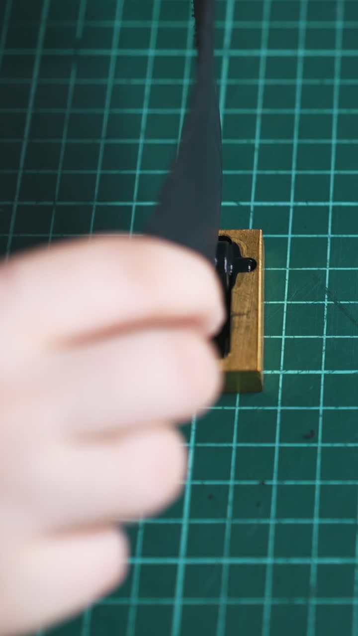 CU: Professional tailor colours leather strip edges with pure copper and demonstrates detail in workshop close view