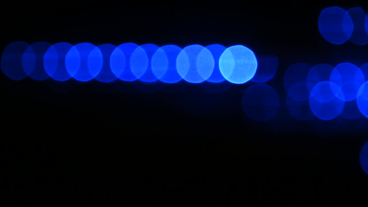 파란색 보케 서클이 검은색 배경 위로 이동합니다.
