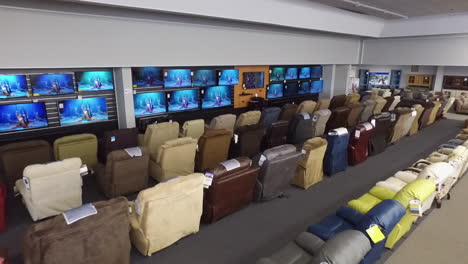 tiro de drone dentro de una tienda de muebles, con televisores y sillones reclinables