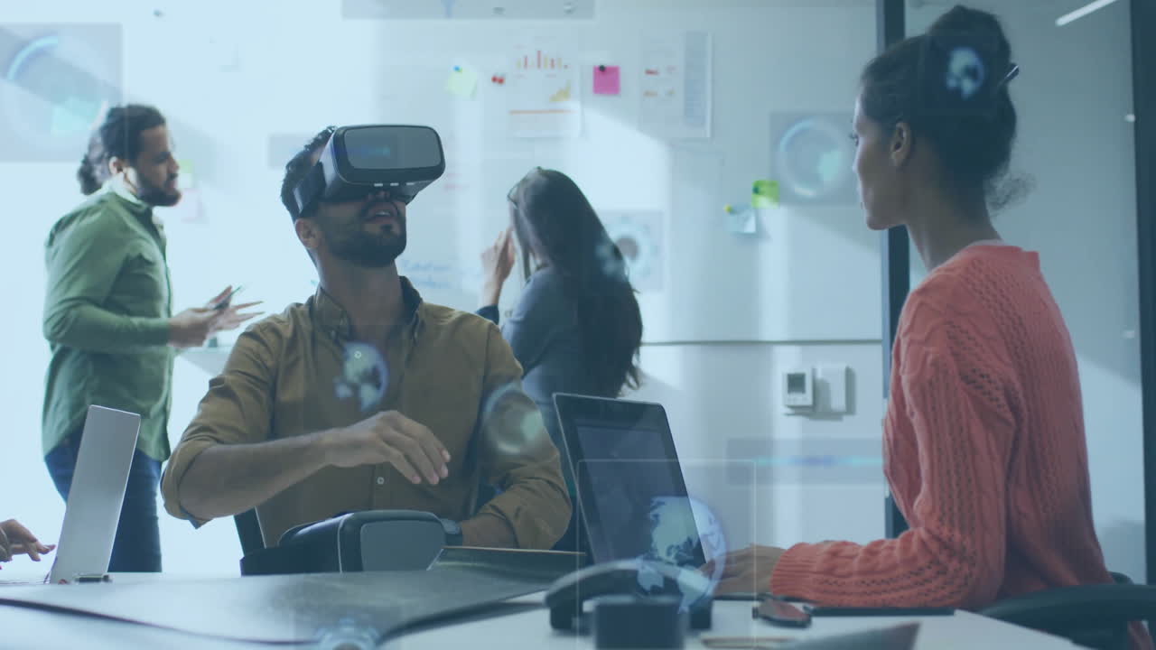 Technology team collaborating at table, man wearing VR headset exploring floating data charts