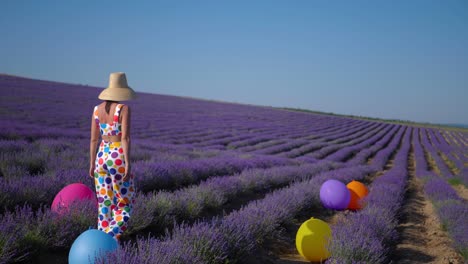 woman in a multicolored suit with circles and a hat holds large inflatable