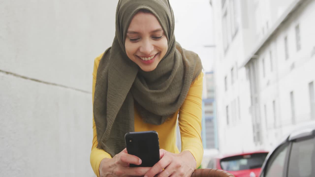 Woman wearing hijab using her phone on a bike