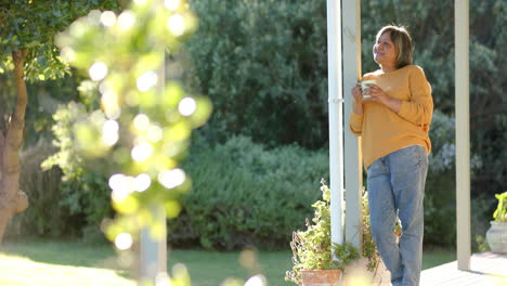 Happy-senior-biracial-woman-drinking-coffee-on-terrace,-slow-motion,-copy-space