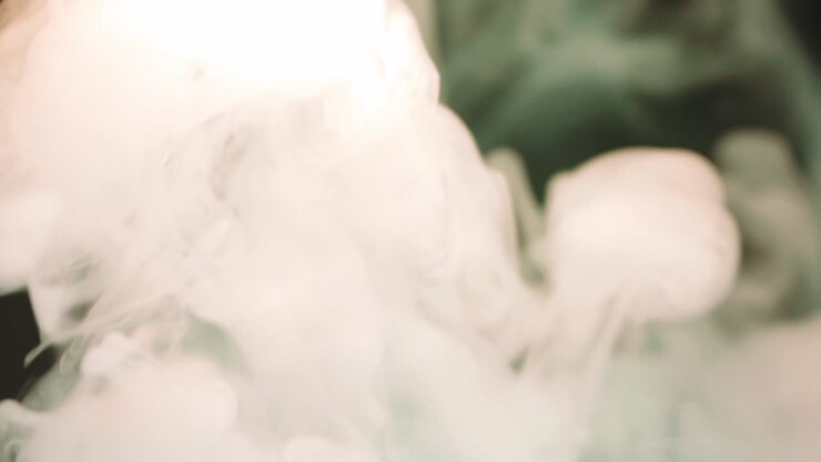Movimento astratto di fumo e vapore verde e arancione su sfondo scuro, illuminato dalla luce.