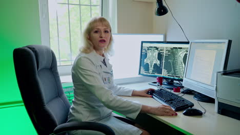 doctor working in monitoring room. professional technical doctor sitting at desk with multiple displays in hospital