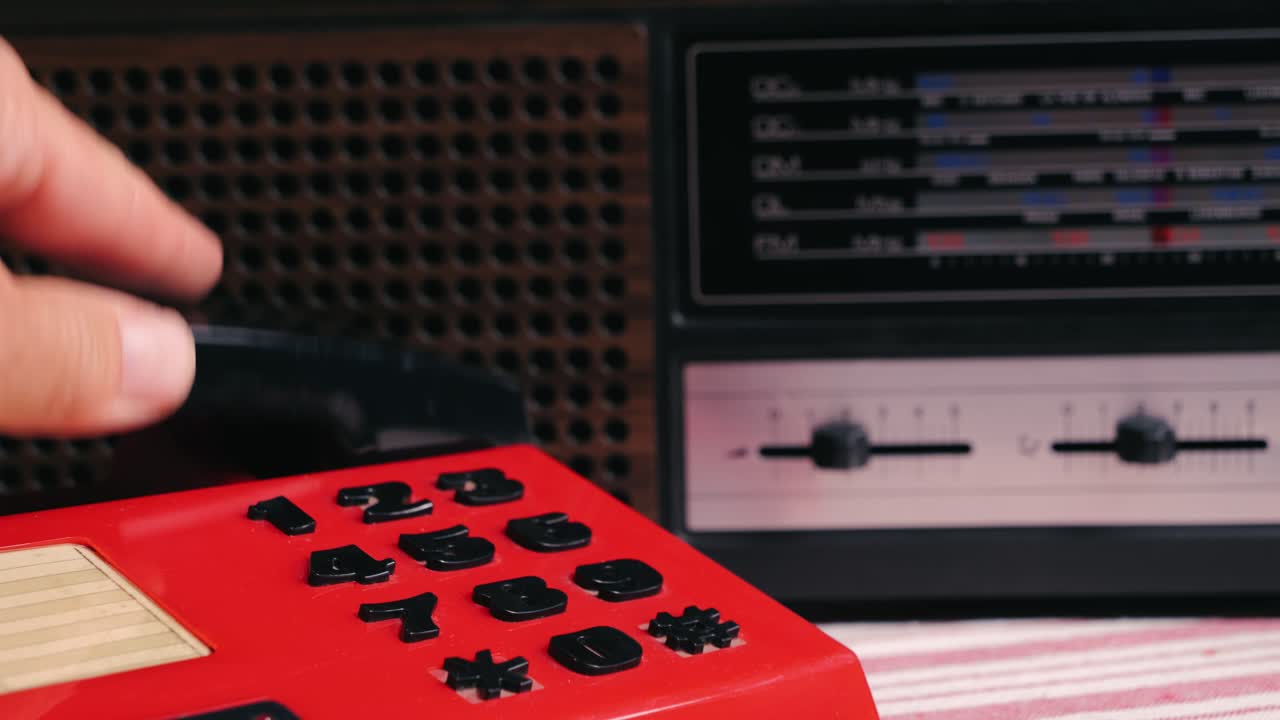 Retro vintage red phone, telephone is displayed on a wooden desk, adding a nostalgic touch. Man answer for call on button 90 phone.