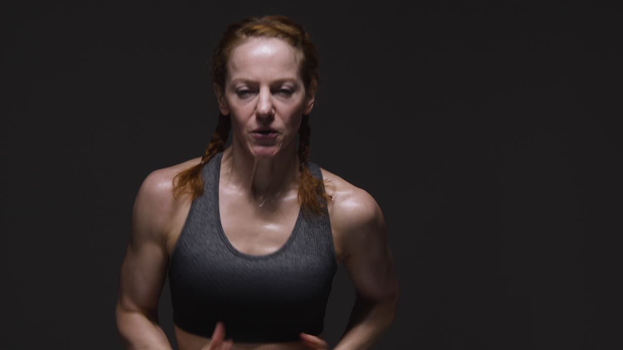 fotografía de estudio de una mujer madura con ropa de gimnasia haciendo ejercicio de cardio corriendo en el lugar 1