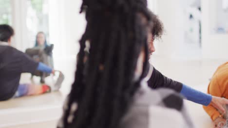 biracial male dancer stretching with diverse colleagues in dance studio, slow motion
