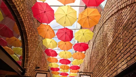 vibrant umbrellas hanging between brick buildings