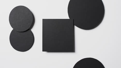 video of close up of square and circles of black paper and copy space on white background