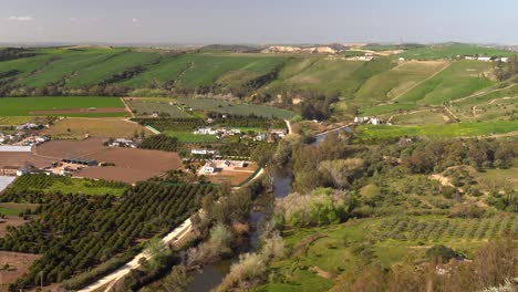 Beautiful-rural-countryside-with-green-hills-and-small-river,-tilt-up-shot