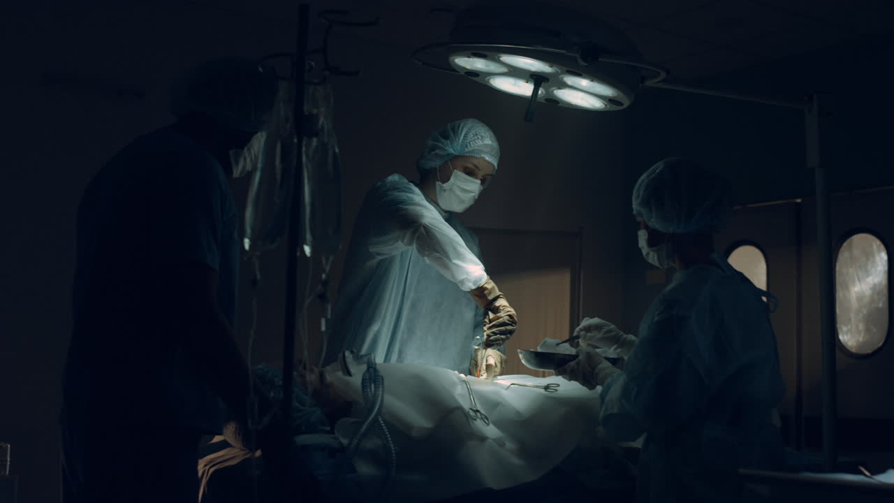 Confident surgeon performing operation in dark sterile clinic emergency room.