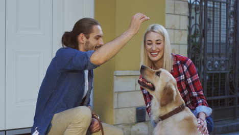 Vista-De-Cerca-Del-Hombre-Sentado-Con-Su-Novia-Al-Aire-Libre-Y-Entrenando-A-Su-Perro-Labrador