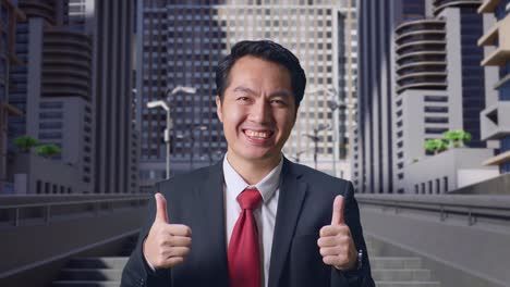 an asian business man showing thumbs up gesture and smiling while standing in city