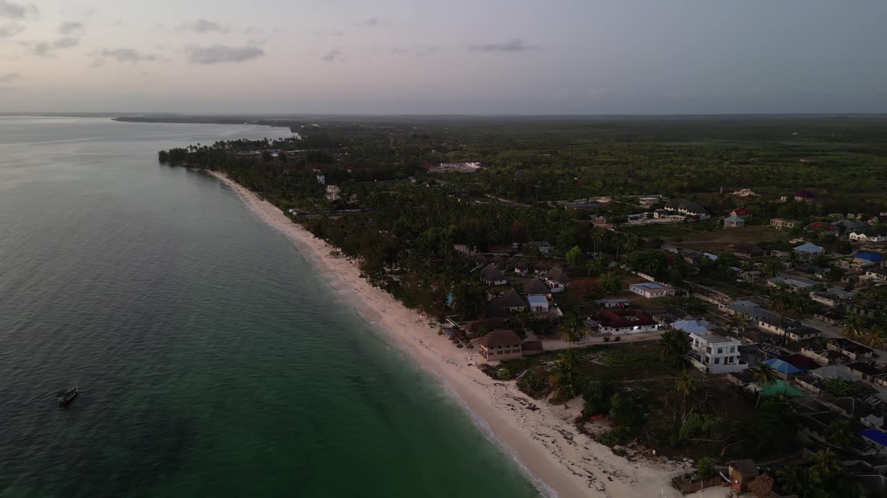 Các khu nghỉ dưỡng và nhà ở bãi biển Uroa trên Đảo Zanzibar, Tanzania, Châu Phi lúc hoàng hôn, cảnh quay lia từ trên cao sang trái