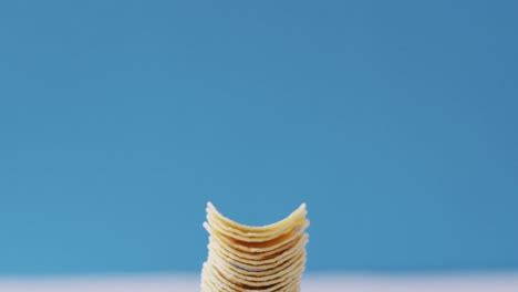 Close-up-view-of-stack-of-potato-chips-with-copy-space-against-blue-background