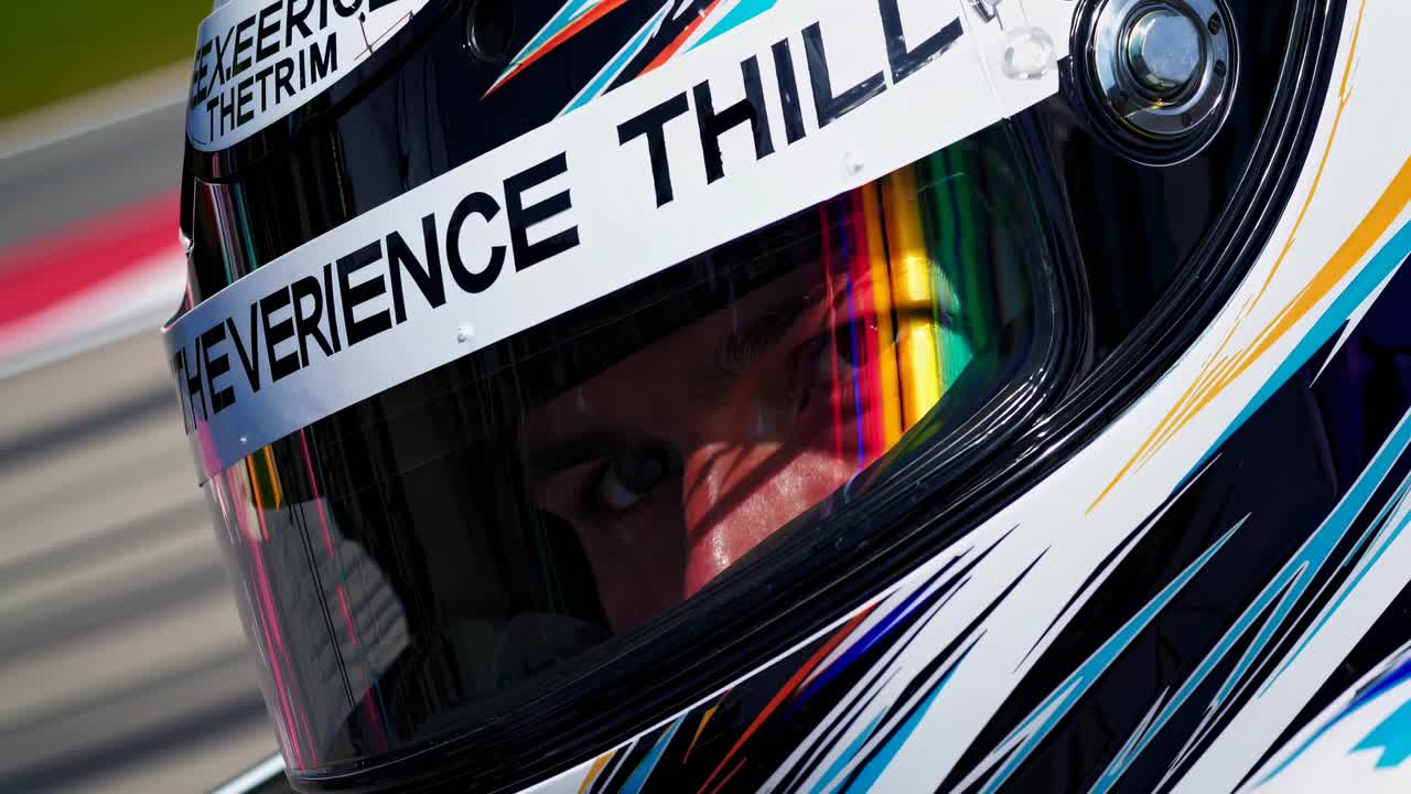 Close-up video shot of a race car driver in a helmet, capturing intense focus and vibrant
