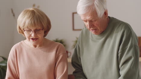 elderly couple cooking salad together in kitchen