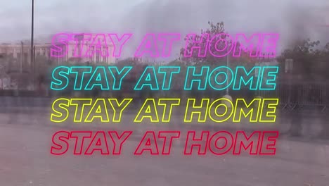 Animation-of-four-lines-of-colourful-neon-words-Stay-At-Home-over-people-walking-on-a-street