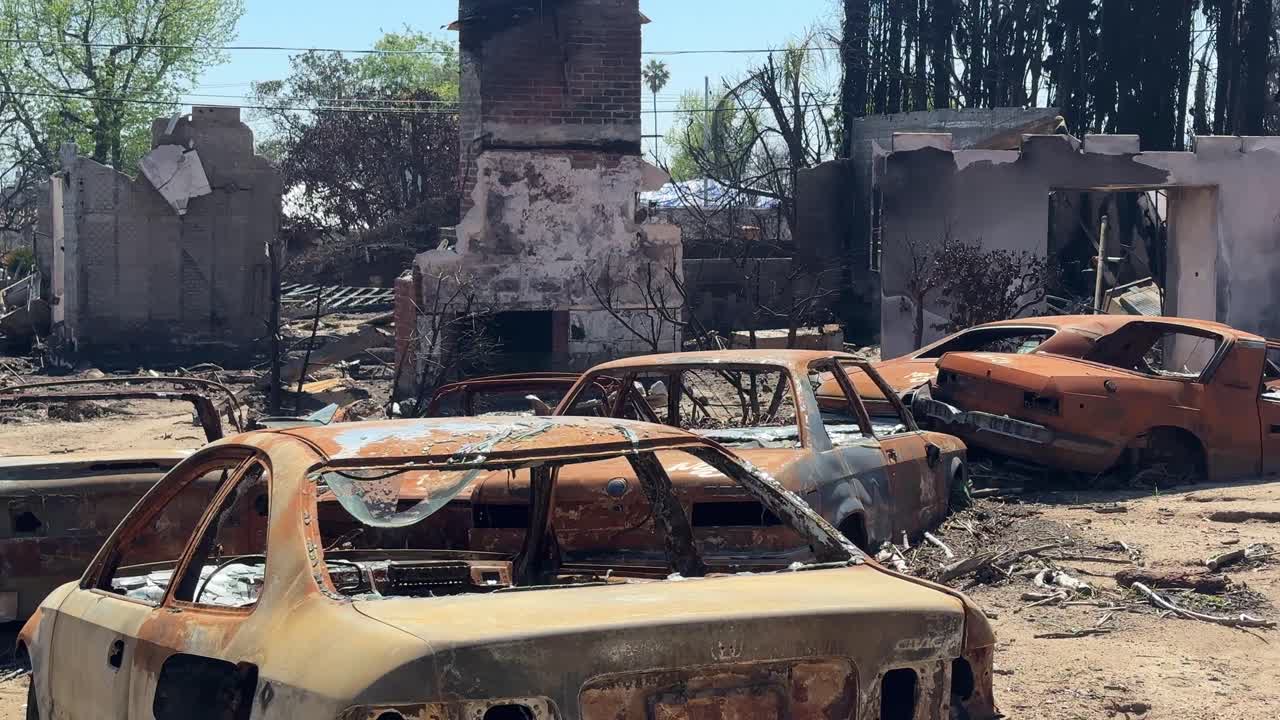 Handheld close-up panning shot of burned vehicles in the aftermath of the Eaton Fire in Altadena, California. 4K