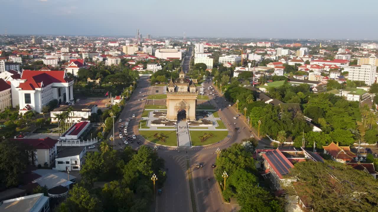 avión volando hacia el monumento patuxai en vientiane con tráfico ligero que lo rodea