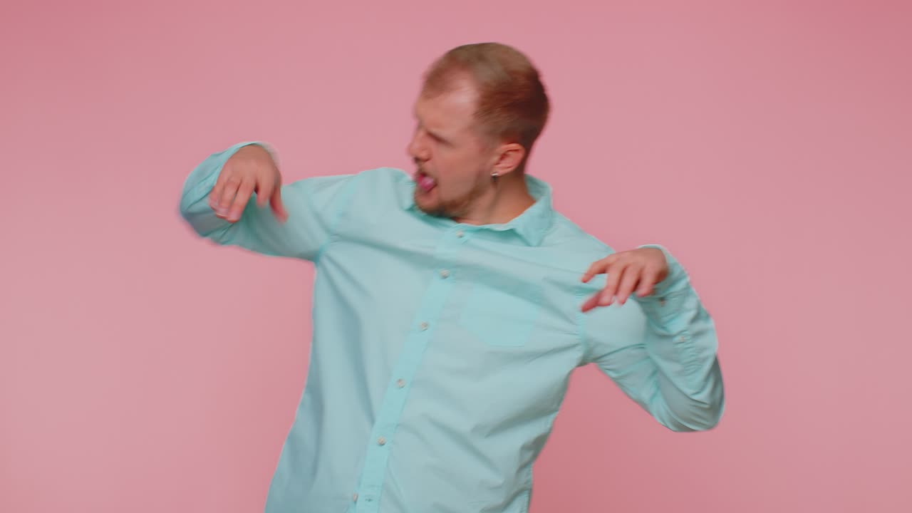 Funny joyful man making playful silly facial expressions grimacing fooling around showing tongue