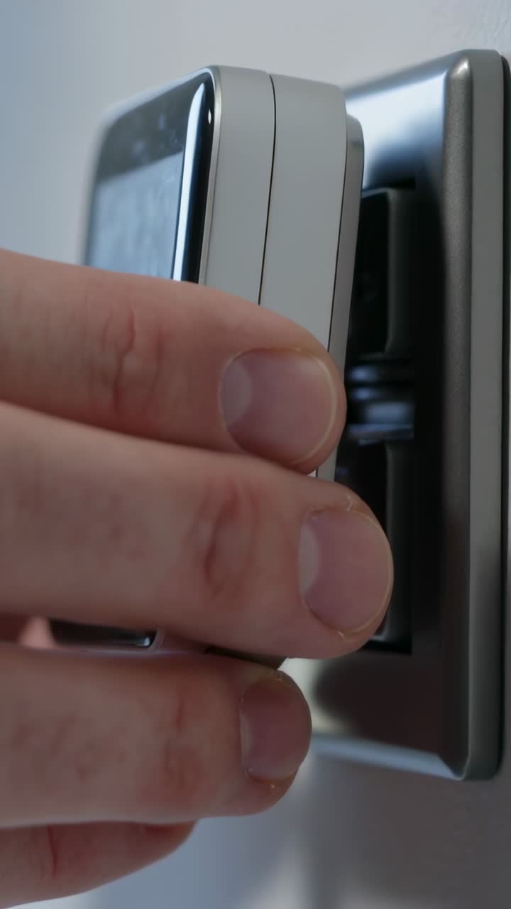 Vertical video: Approaching right hand securing small device onto metal bracket at home to mount
