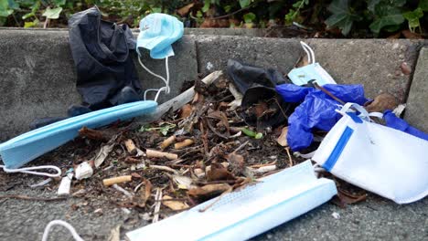 mascarillas desechables sucias para el virus de la corona y guantes de látex entre la basura de los cigarrillos en el pavimento de la acera de la calle dolly right