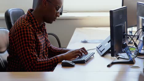 Side-view-of-young-black-businessman-working-at-desk-in-a-modern-office-4k