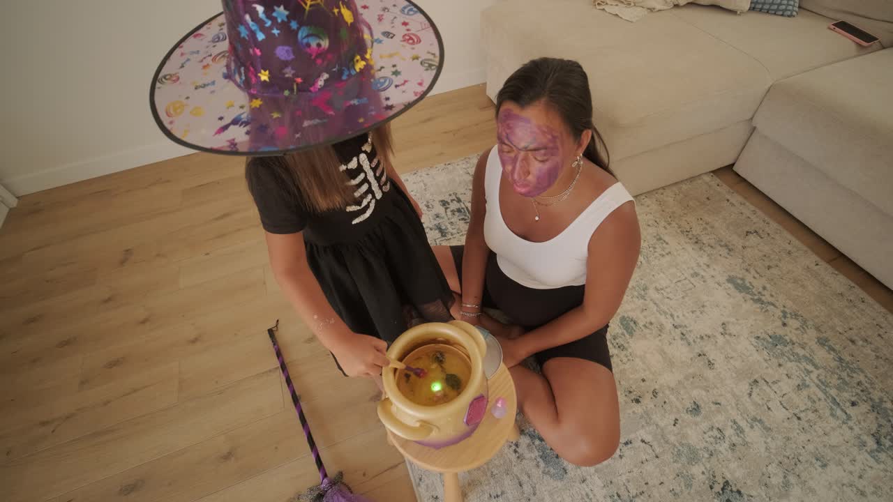 una niña vestida de bruja jugando con su madre embarazada en casa