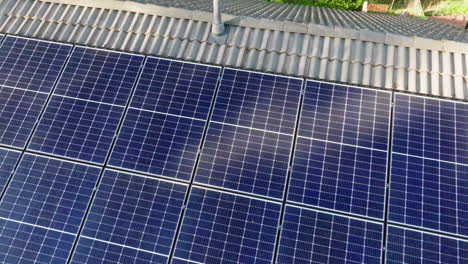 drone rising above partly shadowed solar cells on a house roof, summer evening
