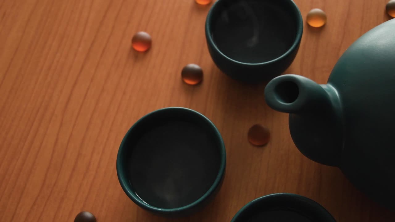 fondo mínimo de un juego de té verde japonés con vapor saliendo de las tazas, sobre una mesa de madera, con algunas piedras alrededor